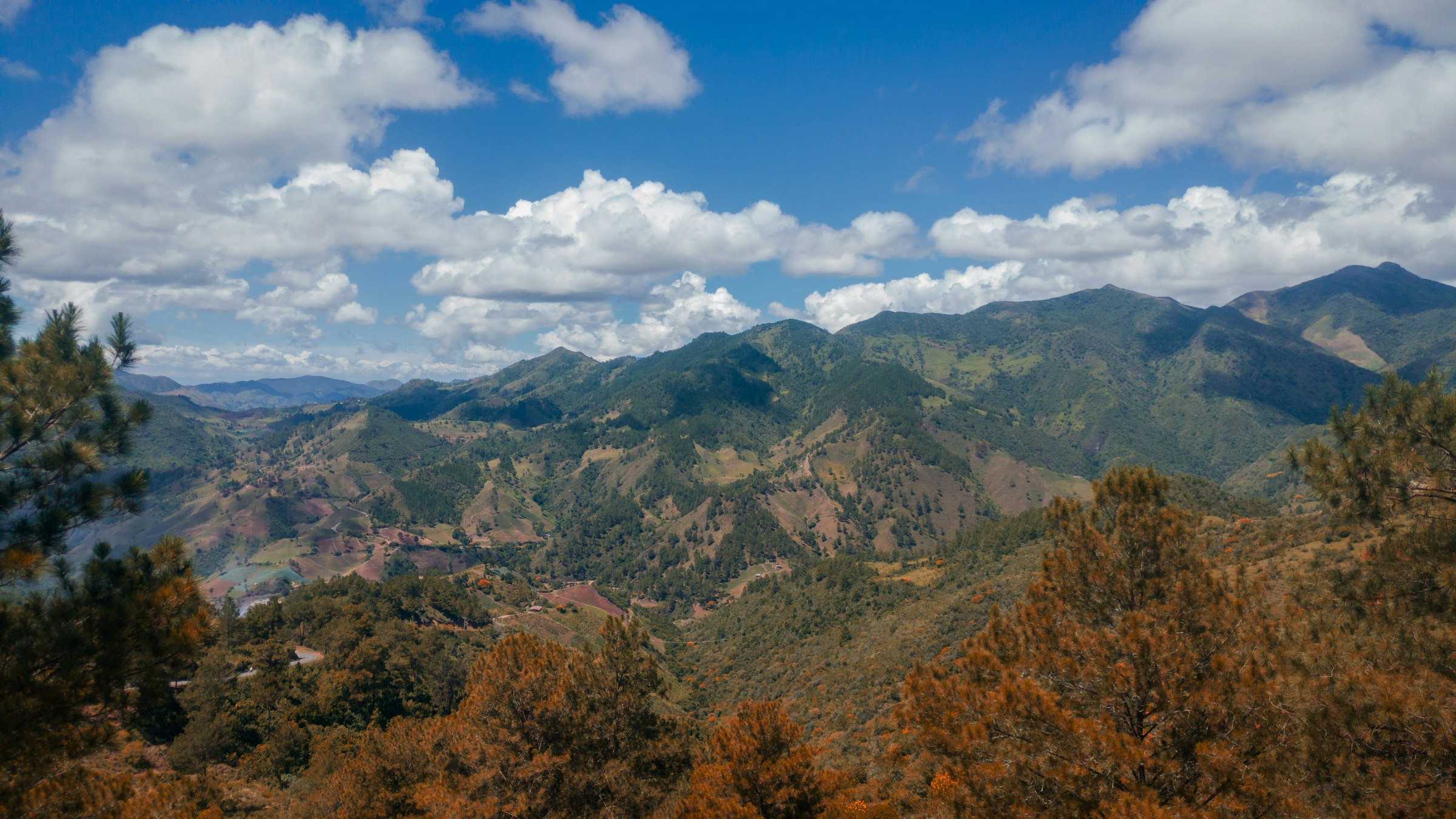 Montañas y pinares de la Cordillera Central dominicana bajo un cielo con nubes